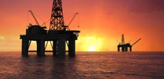 Oil rig silhouette over orange sky
