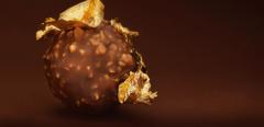 Chocolate praline with edible gold on dark brown background low key