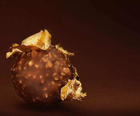 Chocolate praline with edible gold on dark brown background low key