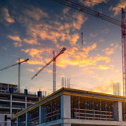 Construction of a new residential complex.Several high-rise cranes against the backdrop of a beautiful sunset sky.