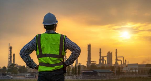 Asian engineers looking at site in oil and gas refinery or Petrochemical factory during sunrise, industrial concept.