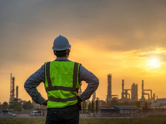 Asian engineers looking at site in oil and gas refinery or Petrochemical factory during sunrise, industrial concept.