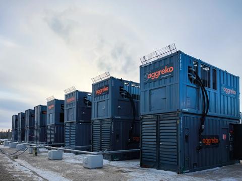 Multiple dark industrial units by Aggreko stacked outdoors in a cold environment.