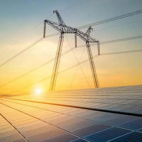 High voltage pylons with electric power lines transfering electricity from solar photovoltaic sells at sunrise. Production of sustainable energy concept.