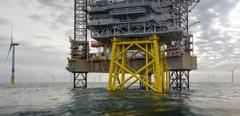 View on offshore wind-farm with 8MW wind-turbines and offshore platform in German north Sea with dramatic clouds