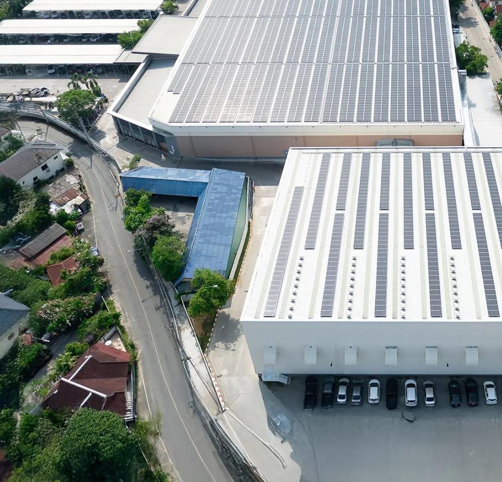 Aerial view of industrial warehouse buildings with rooftop solar panels installed.