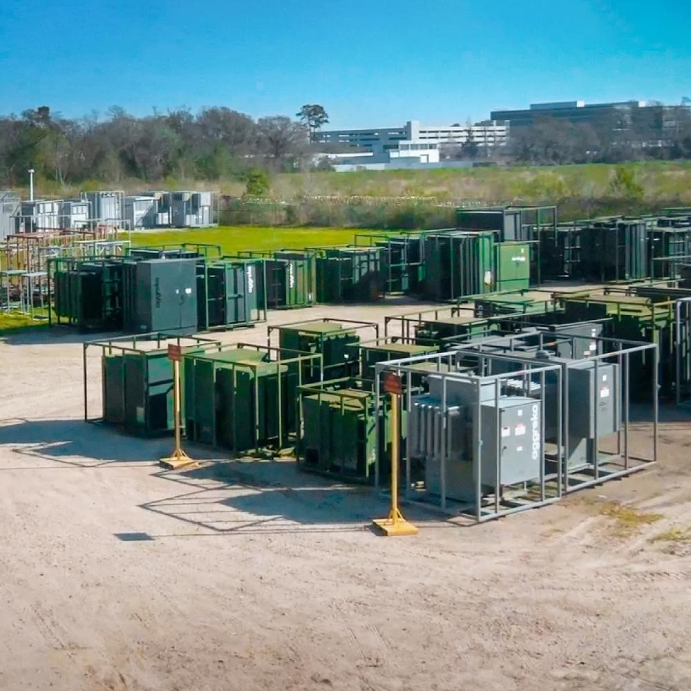 View of multiple Aggreko grey transformers amongst other green equipment at a worksite 