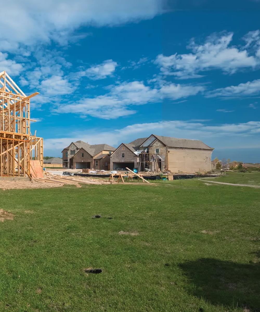 The wooden frame of a house under construction in a green field 