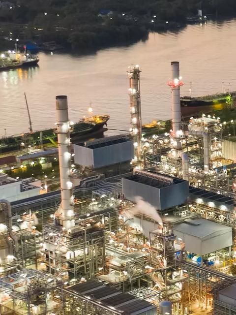 View of a lit up petrochemical refinery plant at night.