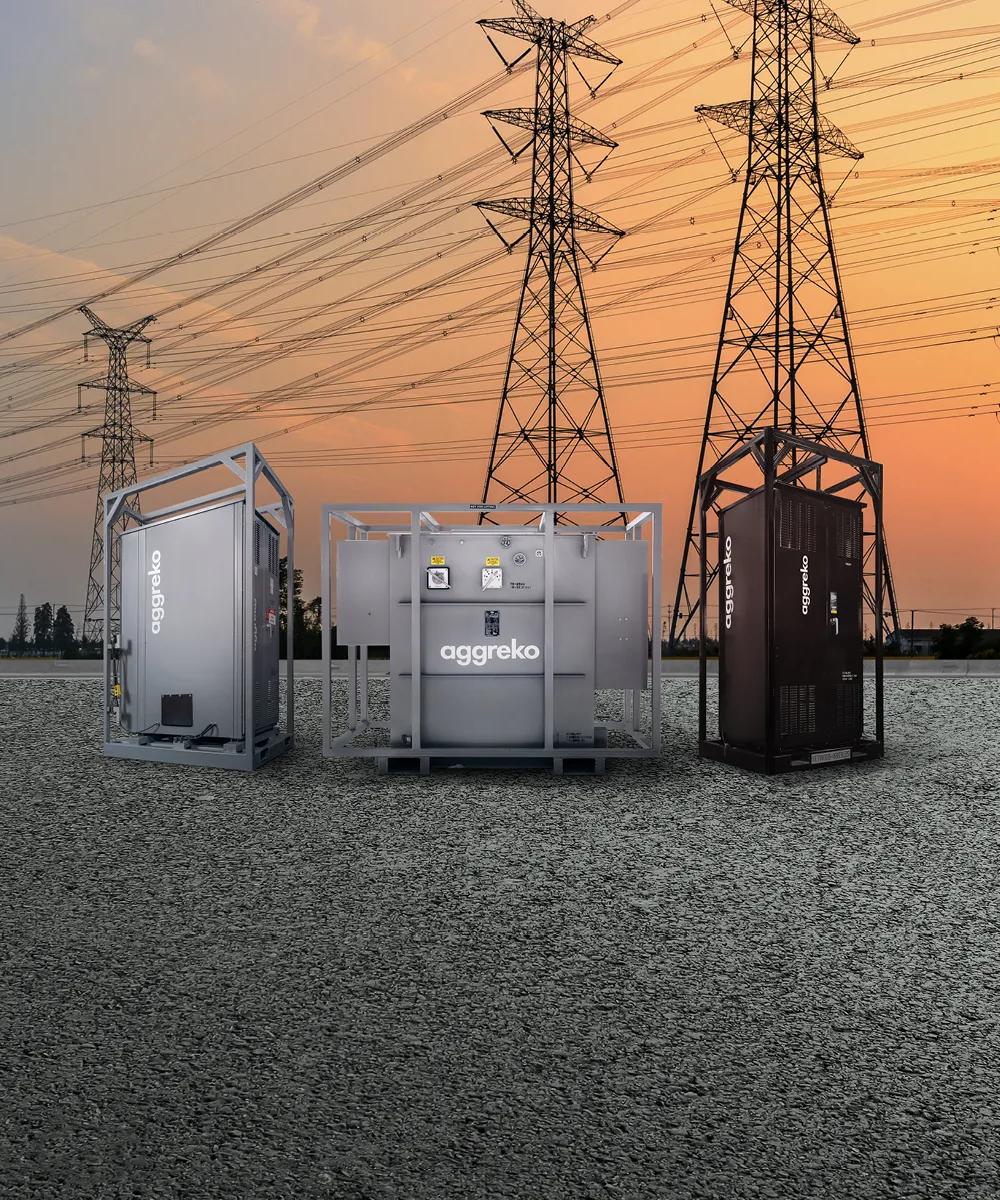 3 Aggreko industrial units outdoors with transmission towers in the background.