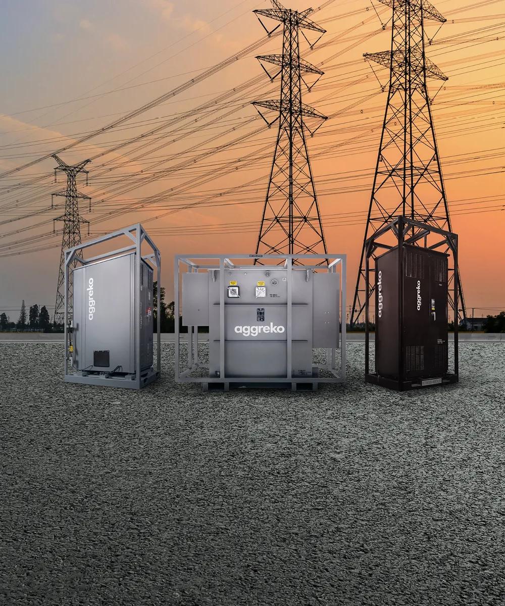 3 Aggreko industrial units outdoors with transmission towers in the background.