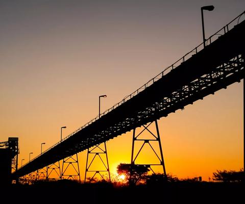 Silhouette of a mining silo and conveyor belts at sunset on a Palladium Platinum Mine