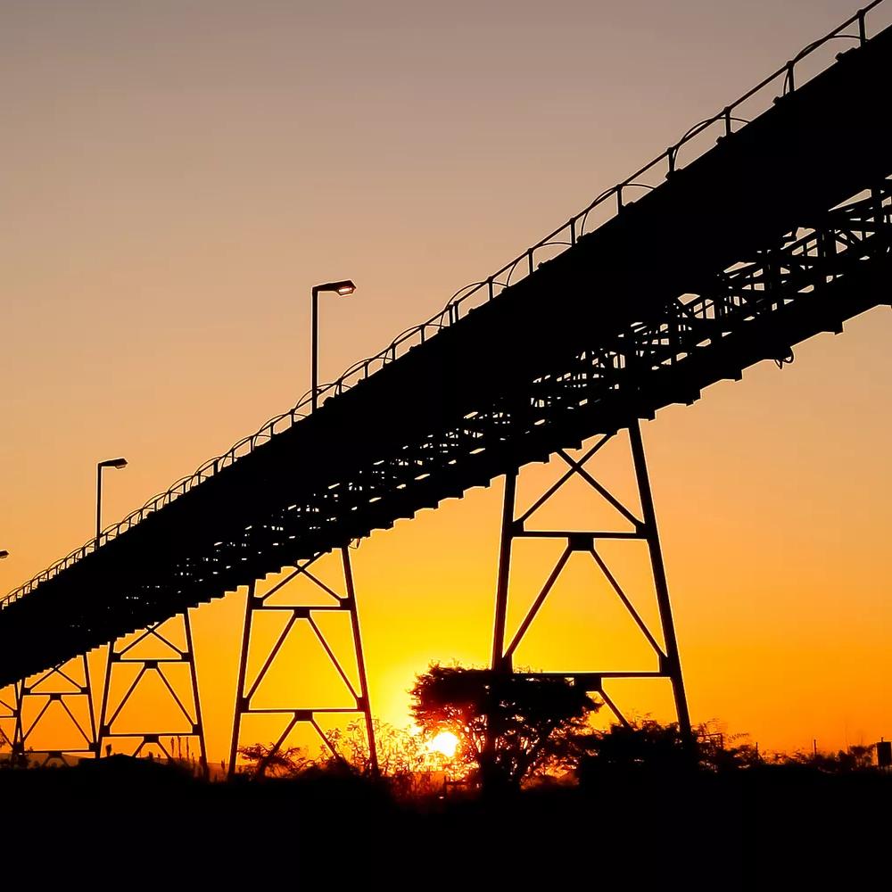  Silhouette of a mining silo and conveyor belts at sunset on a Palladium Platinum Mine.