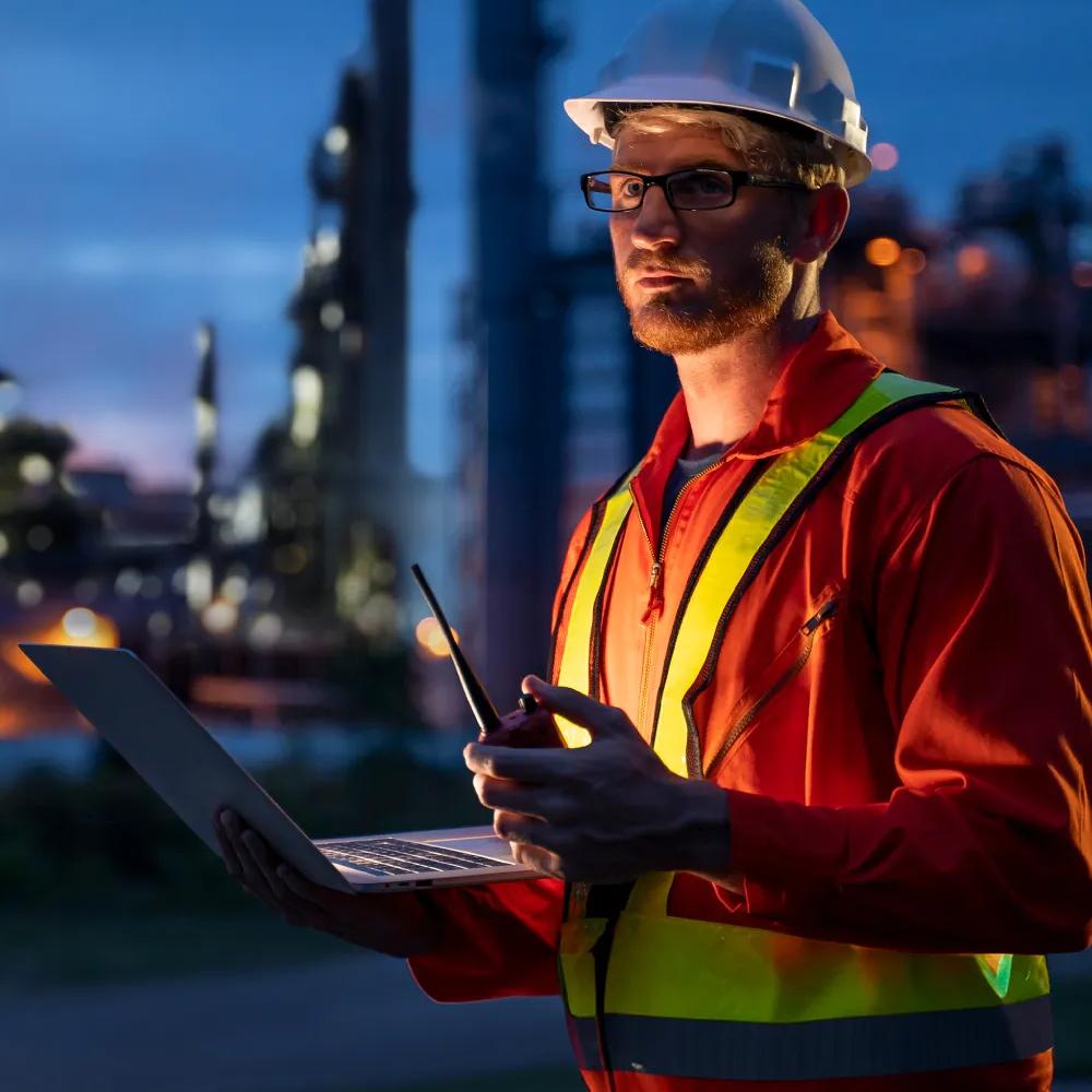 Worker in uniform with a refinery in the background.