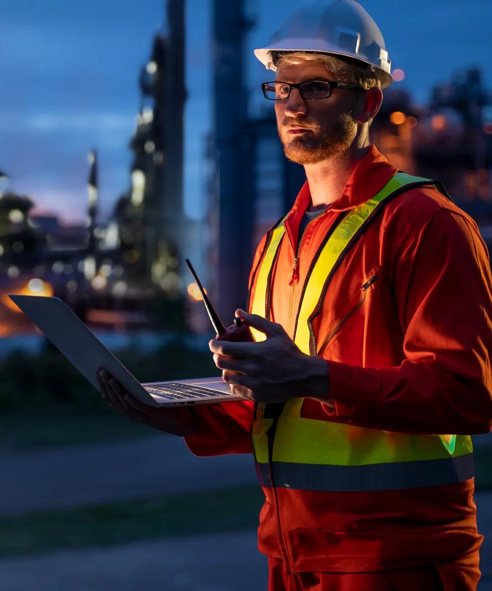 Worker in uniform with a refinery in the background.