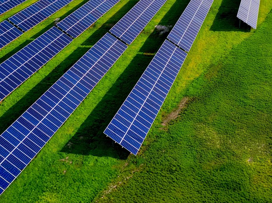 Aerial view of vertical multiple rows of solar panels in a grass field.