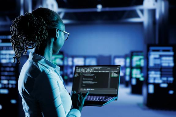 Licensed programmer running code and programming on laptop, troubleshooting and upgrading high tech facility designed to accommodate multiple clusters of fully operational server cabinets