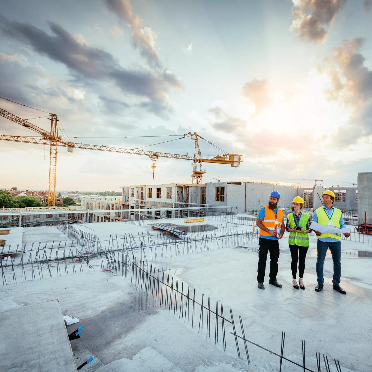 Employees working on construction site, wearing protective equipment and discussing next construction phase