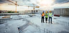 Employees working on construction site, wearing protective equipment and discussing next construction phase