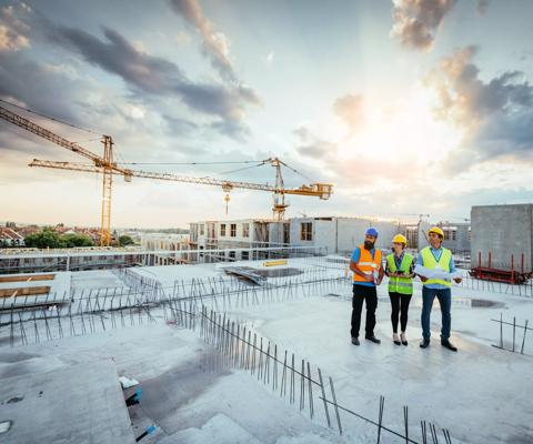 Employees working on construction site, wearing protective equipment and discussing next construction phase
