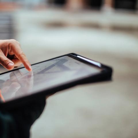 Unrecognizable construction worker hands holding a digital tablet while working outdoors