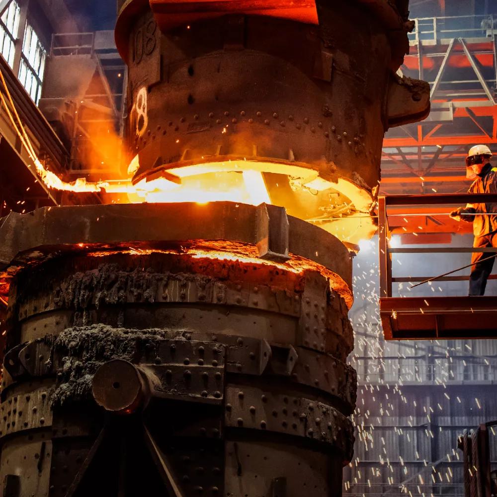 A worker next to a furnace inside a steel plant