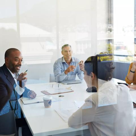 Businessman explaining to coworkers in meeting room, shot threw glass