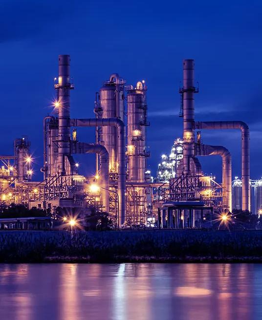 View of a lit up petrochemical refinery plant at night.