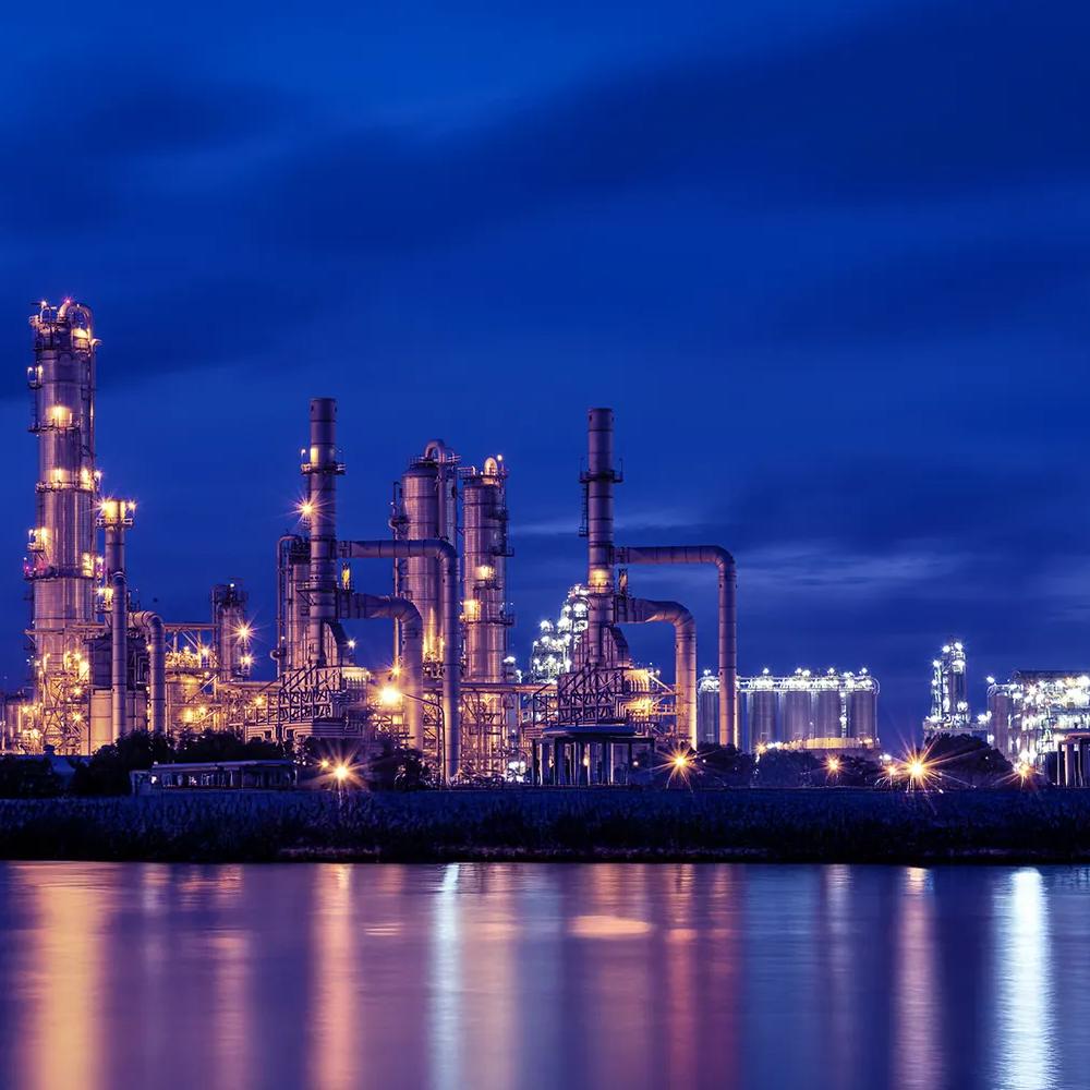 View of a lit up petrochemical refinery plant at night.