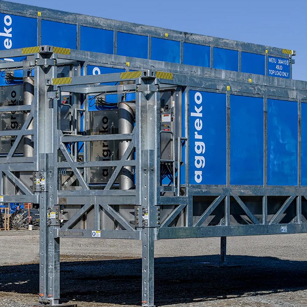 A close-up view of three gray modular frames holding blue industrial Aggreko container units.