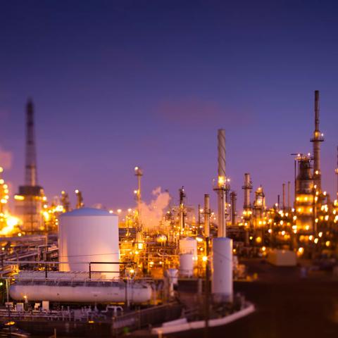 Tilt-shifted photograph of a large oil refinery or chemical plant complex at dusk