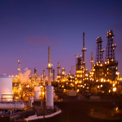 Tilt-shifted photograph of a large oil refinery or chemical plant complex at dusk