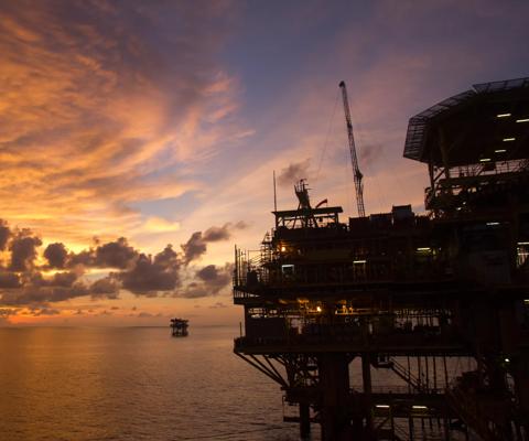 Silhouette of an offshore oil rig at sunset