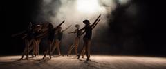 Ballet class on the stage of the theater with light and smoke. Children are engaged in classical exercise on stage.