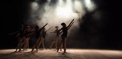 Ballet class on the stage of the theater with light and smoke. Children are engaged in classical exercise on stage.