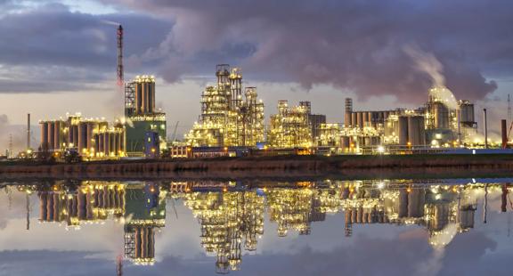 Panoramic view of a refinery lit-up plant with its reflection on the water.