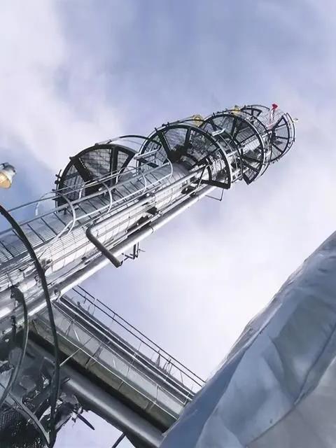 A close-up, low-angle view of the metal framework of an industrial tower or cooling structure against a pale sky.