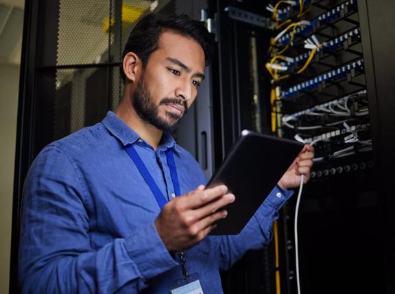 Server room, tablet and engineer with connection cable for maintenance or software update at night. Cybersecurity, it programmer and coder man with technology for database networking in data center