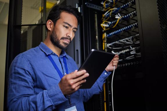 Server room, tablet and engineer with connection cable for maintenance or software update at night. Cybersecurity, it programmer and coder man with technology for database networking in data center