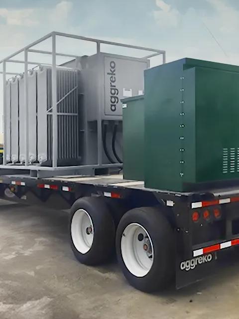 Équipement industriel Aggreko transporté sur une remorque à plateau.