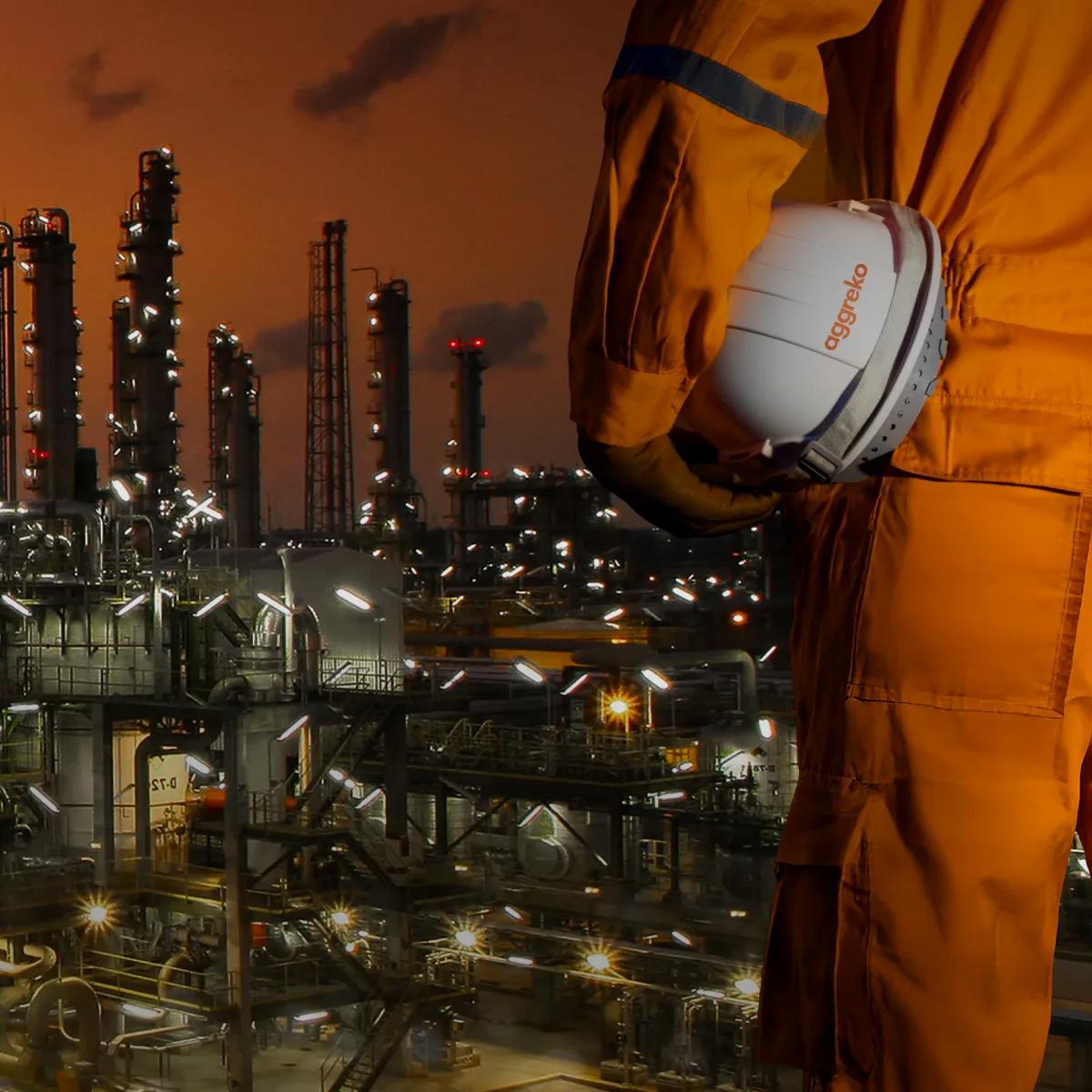Aerial view of a lit-up refinery at night during an orange sunset.