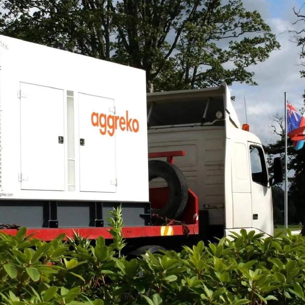 Aggreko equipment mounted on a flatbed trailer displayed alongside international flags.