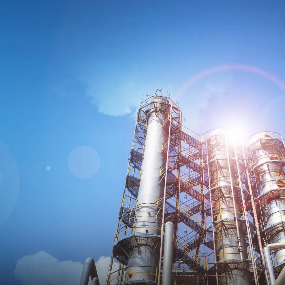Ground view of a refinery's tower under a blue sky