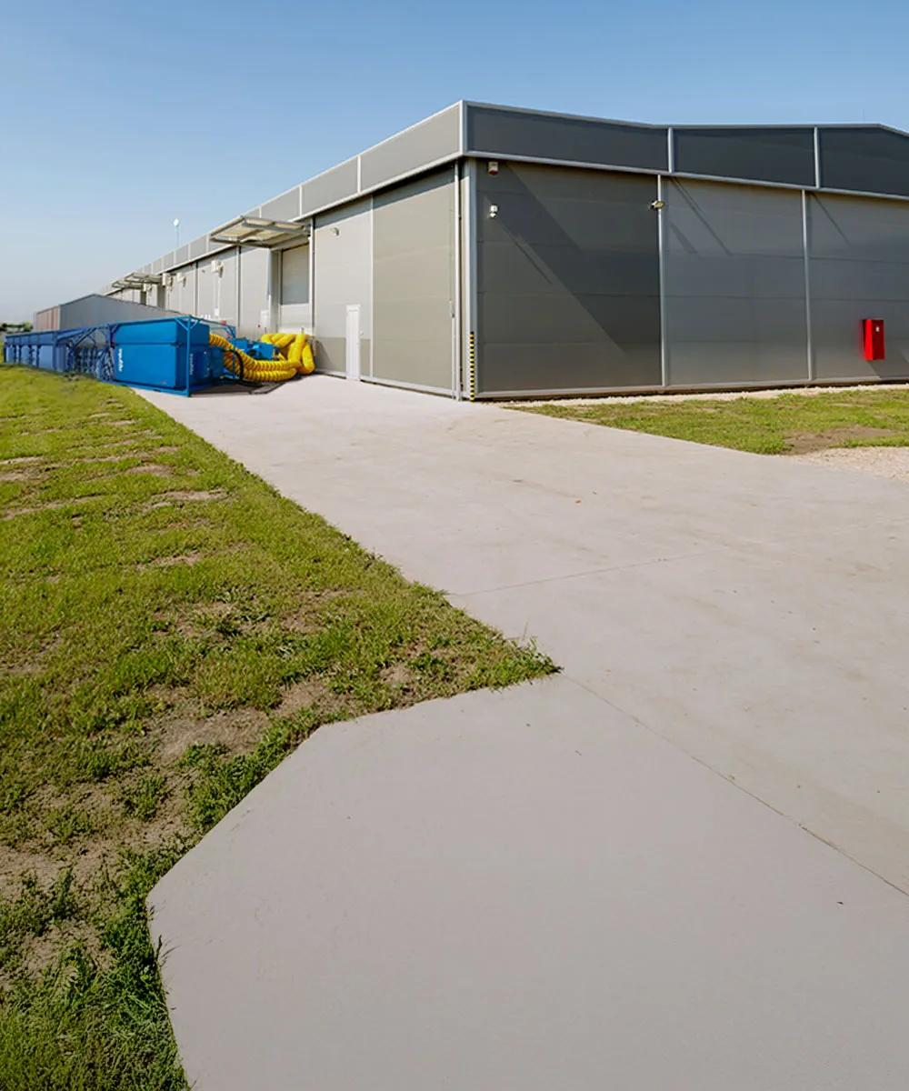 Panoramic view of blue Aggreko cooling equipment outside a building and next to a green field with an electrical plant.