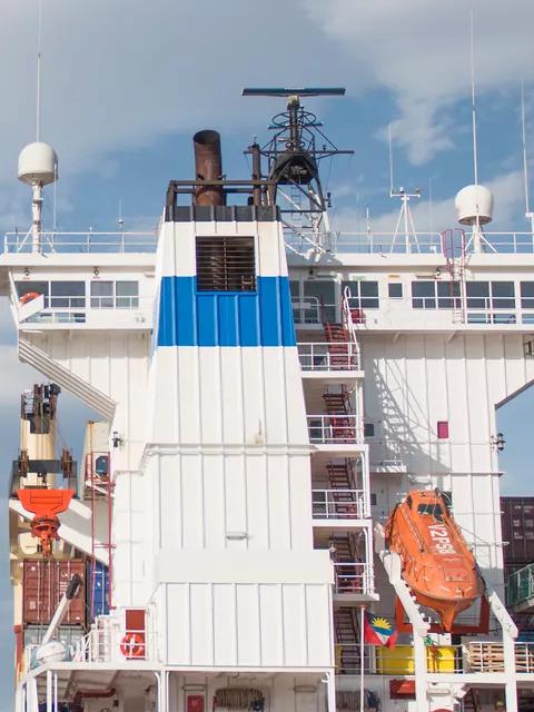 Worker in uniform watching a cargo ship at sea.