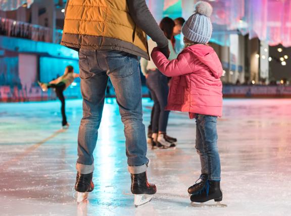 cropped shot of father and daughter holding hands while standing together on skating rink