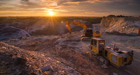 Pelles mécaniques et équipement minier dans une carrière à ciel ouvert au coucher du soleil.