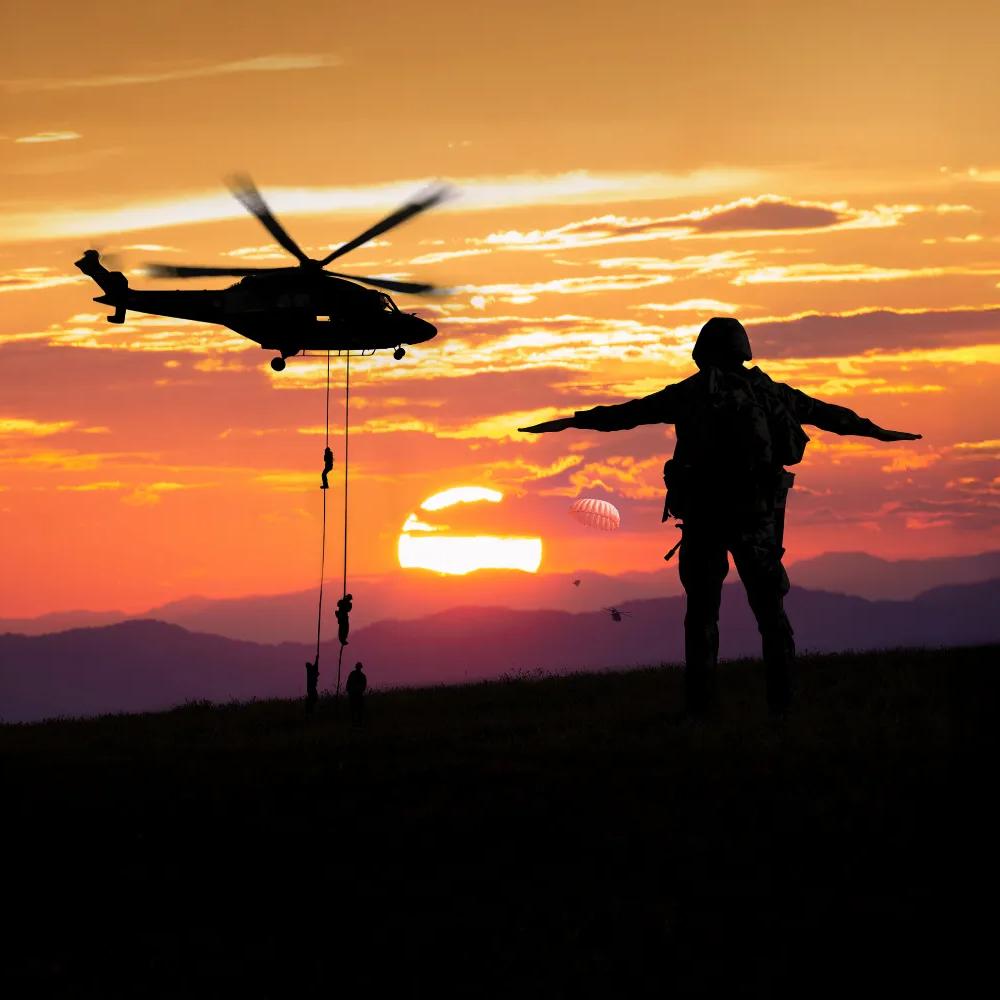 Military helicopter and serviceman silhouette at sunset