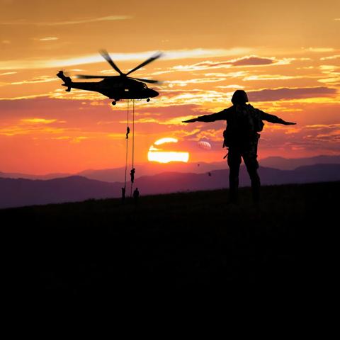 Military helicopter and serviceman silhouette at sunset