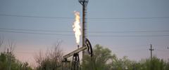 An oil pumping jack, also known as a 'nodding donkey' and flare stack in an oil field in Russia. Photographer: Andrey Rudakov/Bloomberg